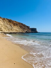 Rocky coast of the ocean bay, clear blue sky, ocean horizon, rocks