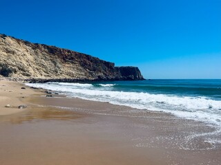 Rocky coast of the ocean bay, clear blue sky, ocean horizon, rocks