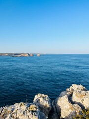 Rocky coast of the ocean bay, clear blue sky, ocean horizon, rocks