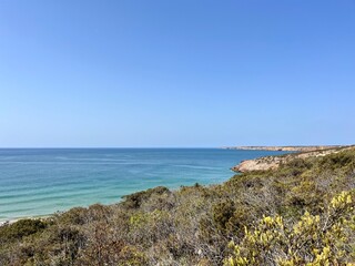 Fototapeta na wymiar Rocky coast of the ocean bay, clear blue sky, ocean horizon, rocks