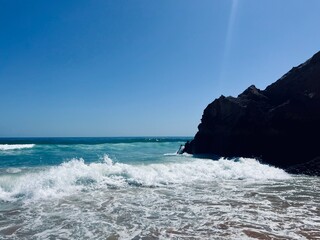 Rocky coast of the ocean bay, clear blue sky, ocean horizon, rocks