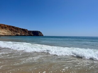 Rocky coast of the ocean bay, clear blue sky, ocean horizon, rocks