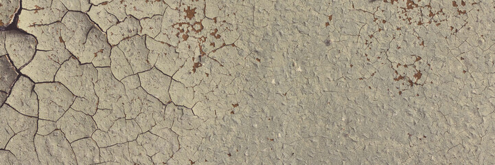 Peeling paint on the wall. Panorama of a concrete wall with old cracked flaking paint. Weathered rough painted surface with patterns of cracks and peeling. Wide panoramic texture for grunge background