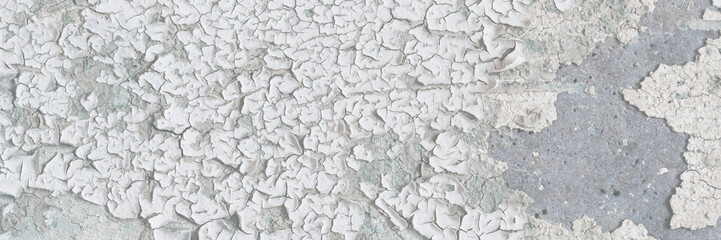 Peeling paint on the wall. Old concrete wall with cracked flaking paint. Weathered rough painted surface with patterns of cracks and peeling. High resolution texture for background and design. Closeup