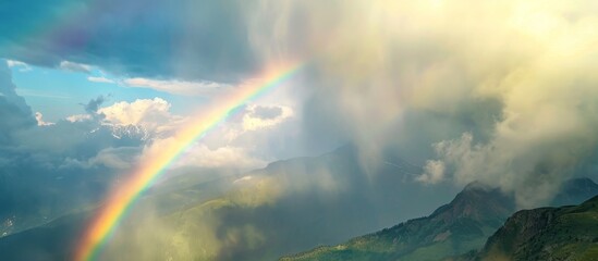 A beautiful rainbow forms in the sky, arching over the majestic mountains and enhancing the natural landscape with its vibrant colors.