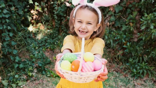 Easter egg hunt. Excited emotion surprise adorable child girl in bunny ears rabbit costume hold basket with Easter colored eggs. Children positive emotions. Kid happy Easter. Egg hunting outside