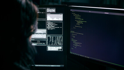 Over The Shoulder Shot Of Female Computer Hacker In Front Of Screens Breaching Cyber Security