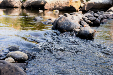 Abstract background stream of water, Waterfall stream on rocks, Rocky riverbank, Calm water stream around the rocks, Stream