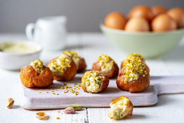 Fritelle with Pistachio Cream Garnish, Eggs, and Cream on White Table