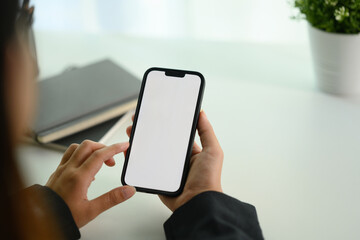 Cropped shot young businesswoman using mobile phone on white office desk