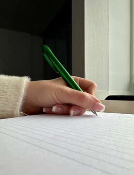 Main qui tiens un stylo vert 