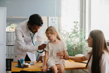 Mother and child seeing family practitioner. Smiling pediatrician with stethoscope checking little girl's lungs.