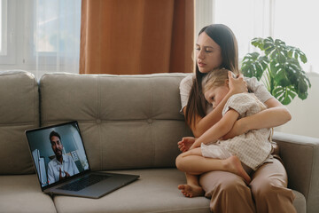 Consultation with a pediatrician online. A young mother with a sick child makes a video call to her...