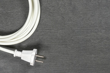 White electrical cable with plug on gray workbench flat lay background with copy space.
