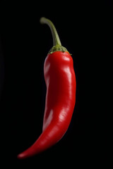 Singular Red Chili Pepper Suspended Against Black Background: Symbol of Spicy Flavors
