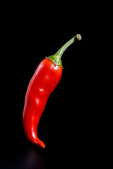 Singular Red Chili Pepper Floating on a Pitch Black Background: Essence of Spice and Simplicity