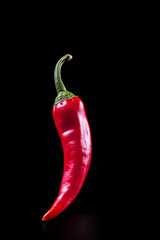Singular Red Chili Pepper Suspended Against Black Background: The Essence of Spicy Flavors