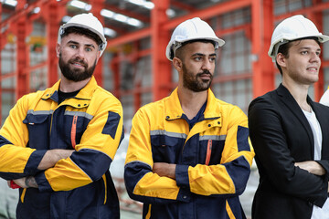 Group of people wear safety helmet uniform standing together in factory. Engineer technician team in hardhat working in manufacturing. Multicultural colleague caucasian latin men in steel production.