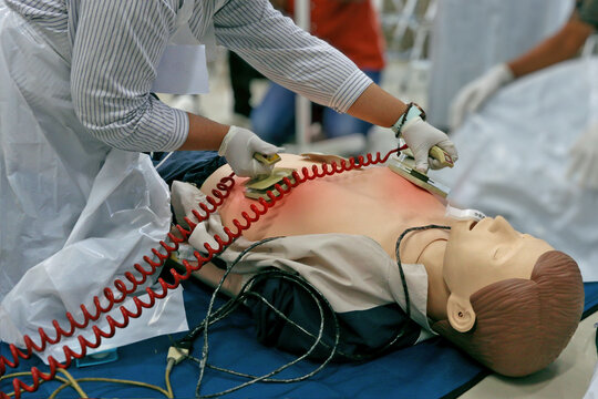 Doctor intensivist performs defibrillation to critical patient. Paramedics using defibrillator on a patient
