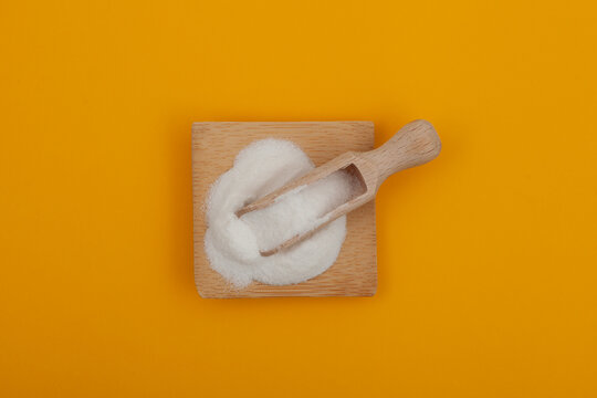 Food additive E316 in measuring scoop on yellow background. Sodium erythorbate, Sodium D-isoascorbate or araboascorbic acid. Chemical formula C6H7NaO6. White crystalline powder