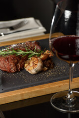 Succulent grilled beef steak with red wine, seasonings, fresh rosemary and grilled vegetables on cutting board