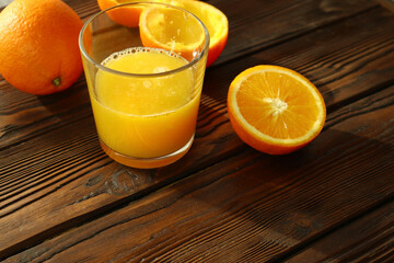  Fresh ripe  oranges  and glass of juice on wooden background   