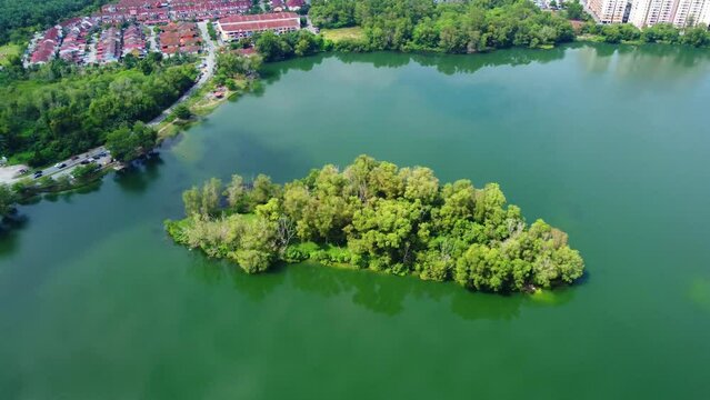 Aerial view of lake surrounded by dense trees and buildings