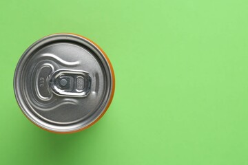 Energy drink in can on green background, top view. Space for text