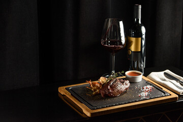 Fototapeta na wymiar Succulent grilled beef steak with red wine, seasonings, fresh rosemary and grilled vegetables on cutting board