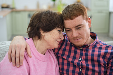 Maternal affection knows no bounds; a mother gently rests her hand on her son, her love as guiding and reassuring as in his childhood.