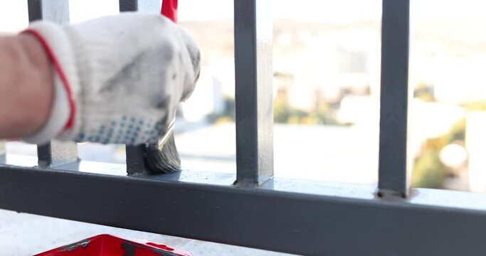 Houseworker paints new railings on balcony of city house