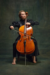 Beautiful woman, talented, passionate cellist looking upward and playing cello against vintage...