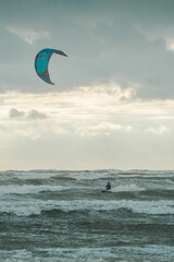 Vertical shot of a Kiteboarder on a stormy sea in a gloomy day