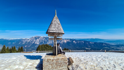 Hiker man at wooden monument at Dreilaendereck, Karawanks, Carinthia, Austria. Triangle border...