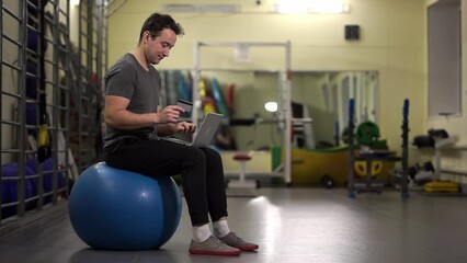 bank card. enters data from a bank card. a man sits on a fitness ball.High-quality footage in 4K format