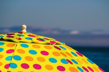 Colorful dotted yellow umbrella on the background of the beach