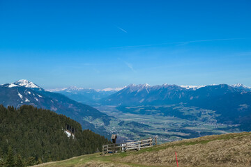 Wooden landmark with scenic view from snow covered alpine meadow on Dreilaendereck in Karawanks, Carinthia, Austria. Alpine landscape in spring, Austrian Alps. Looking at mountain peak Dobratsch