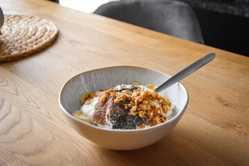 Breakfast bowl with yogurt, banana, chocolate protein, walnuts and chia seeds in a ceramic bowl