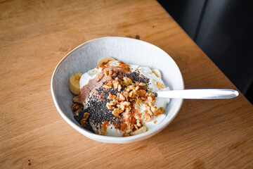 Breakfast bowl with yogurt, banana, chocolate protein, walnuts and chia seeds in a ceramic bowl