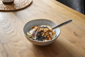 Breakfast bowl with yogurt, banana, chocolate protein, walnuts and chia seeds in a ceramic bowl