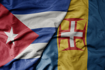 big waving national colorful flag of madeira and national flag of cuba .