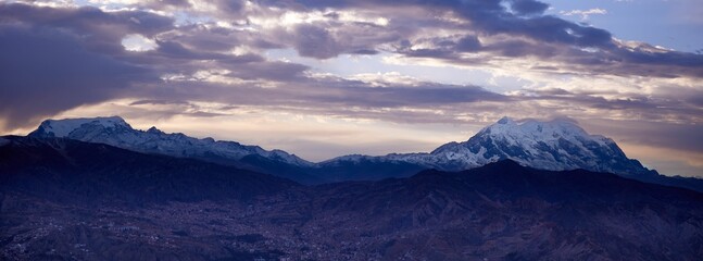 View of snow-capped Illimani mountain with clouds floating above its peak at sunset. Bolivia.