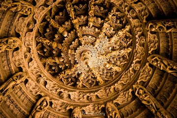 Low angle of a decorative wooden ceiling of a dome with Buddha carvings