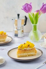 Sliced biscuit cake with cream cheese cream, lemon layer and yellow biscuit decor on a ceramic plate on a light background. Recipes for biscuit cakes.