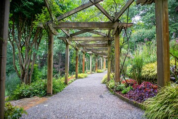 Scenic pathway lined with wooden trellises surrounded by lush green vegetation.