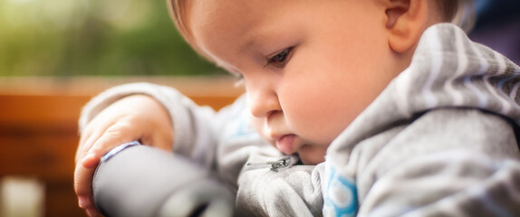 Cute baby boy is deeply engrossed in examining an object with curiosity and concentration,...