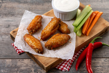 Buffalo spicy chicken wings with cayenne pepper sauce on wooden table.