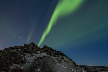 Stunning view of the Northern Lights in Iceland, featuring a vivid green streak glimmering above