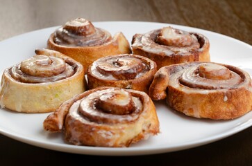 Plate of freshly baked cinnamon rolls, with a sticky caramel topping, ready to be enjoyed.