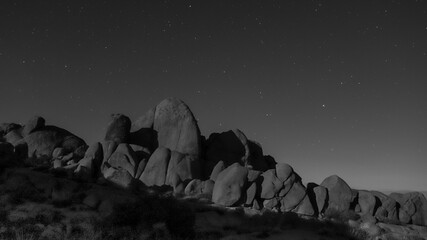 Stunning black and white of a starry night sky over a rocky landscape